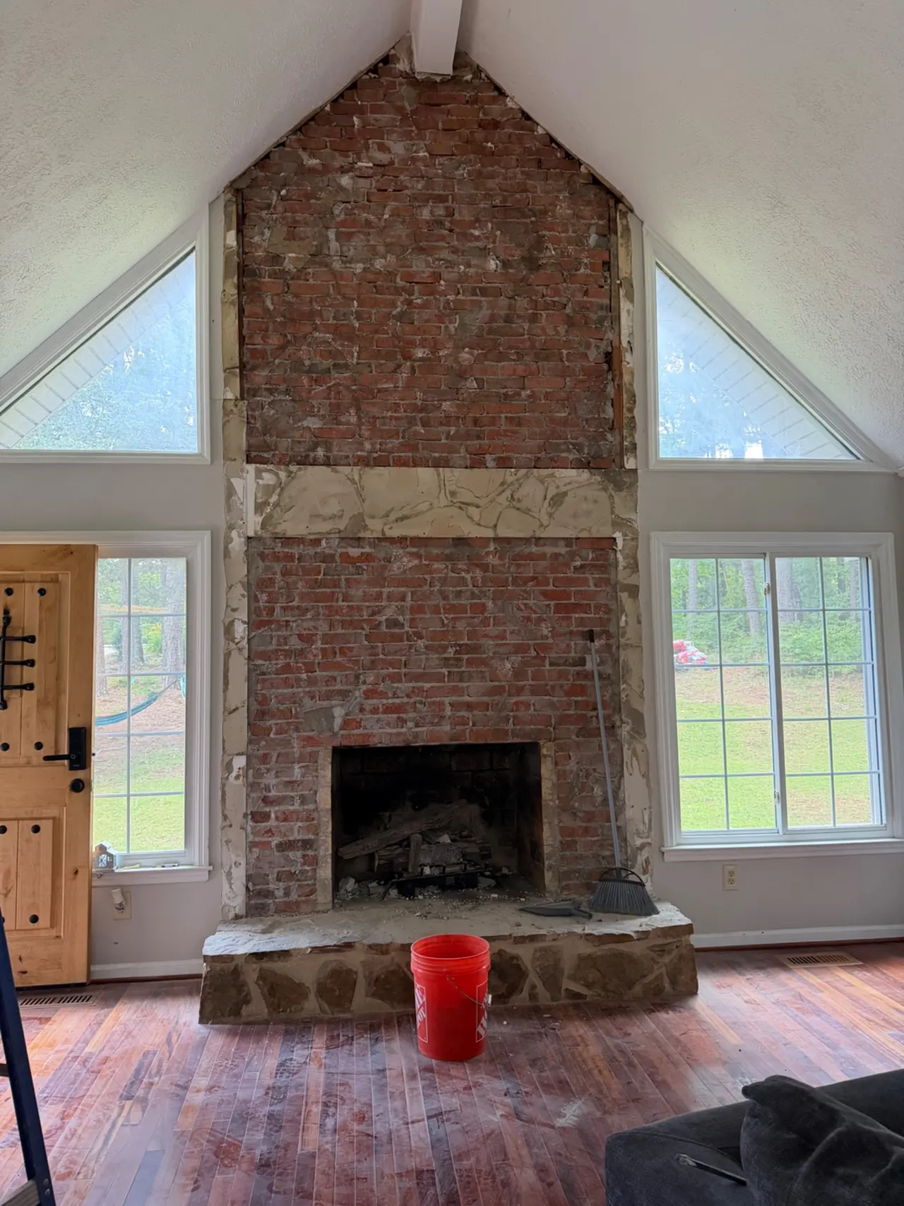 Tall brick fireplace with a stone hearth under a vaulted ceiling before the feature wall was built