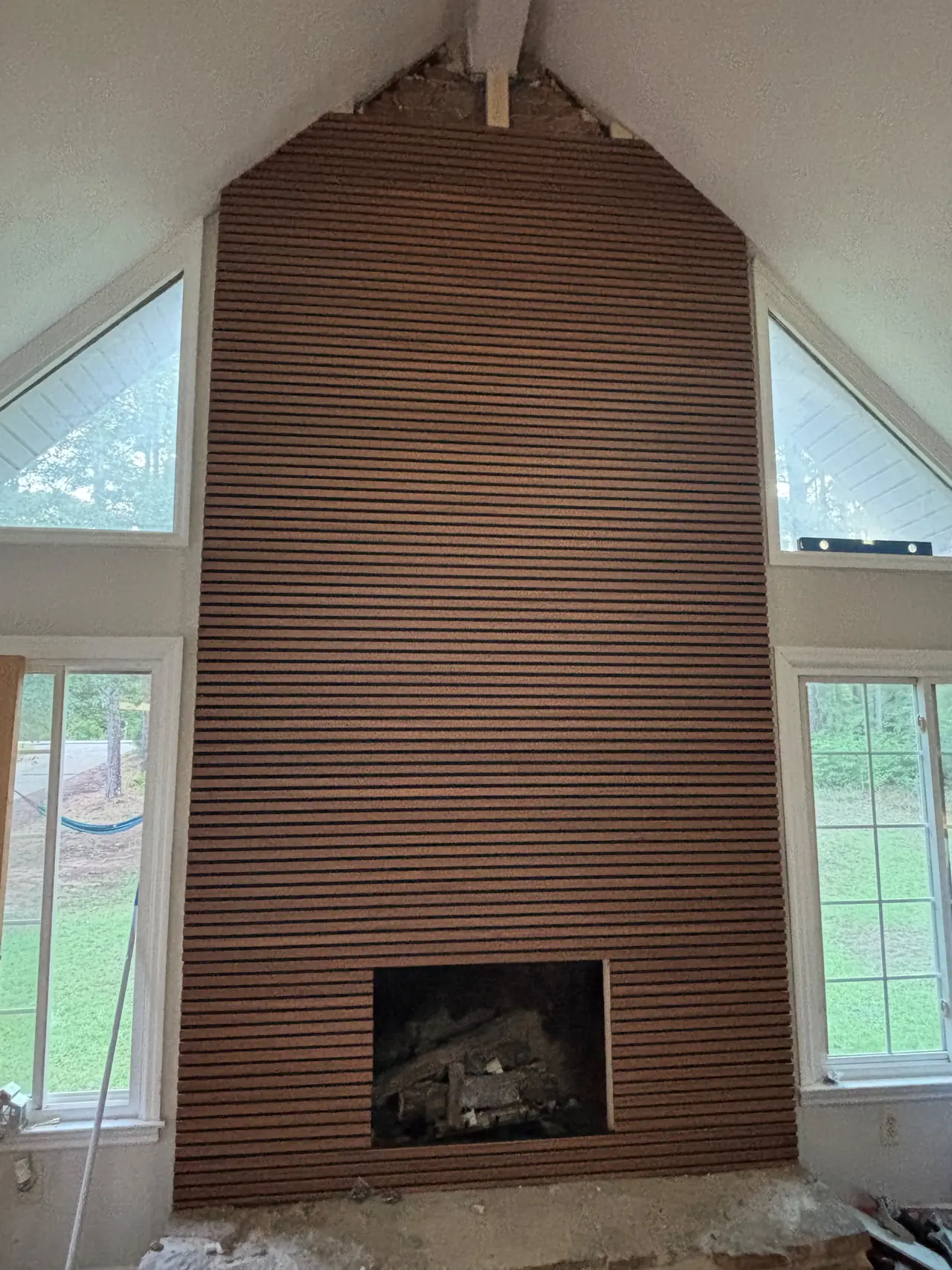 Horizontal wood slats covering the fireplace wall up to the vaulted peak, with the fireplace opening cut out